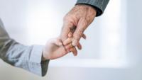 child's hand in elderly person's hand